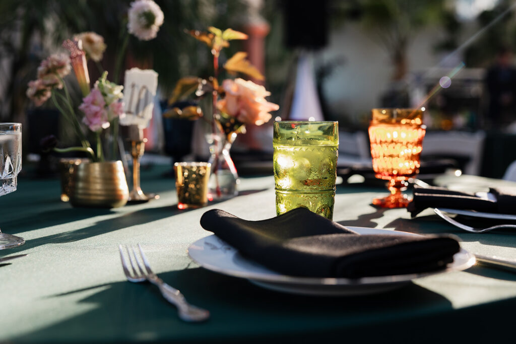 Mismatched colored drinking glasses and antique china on a table with pitcher plant floral centerpieces at a wedding reception at Piper Palm House in St. Louis, Missouri.